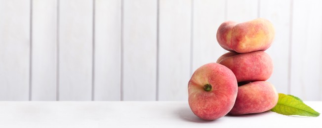 Image of Stack of fresh flat peaches on white table. Banner design with space for text
