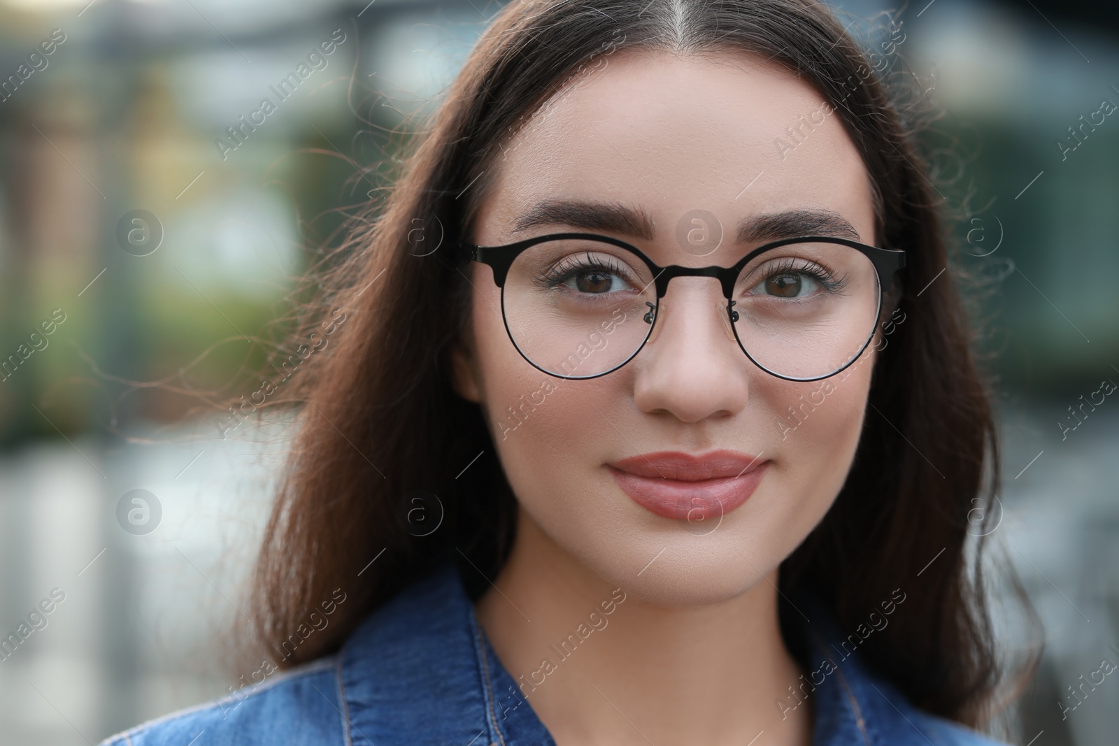 Photo of Portrait of beautiful woman in glasses on blurred background. Attractive lady looking into camera