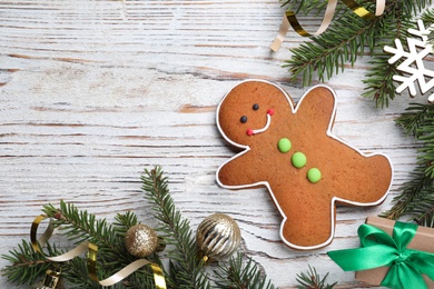 Flat lay composition with gingerbread man on white wooden table, space for text