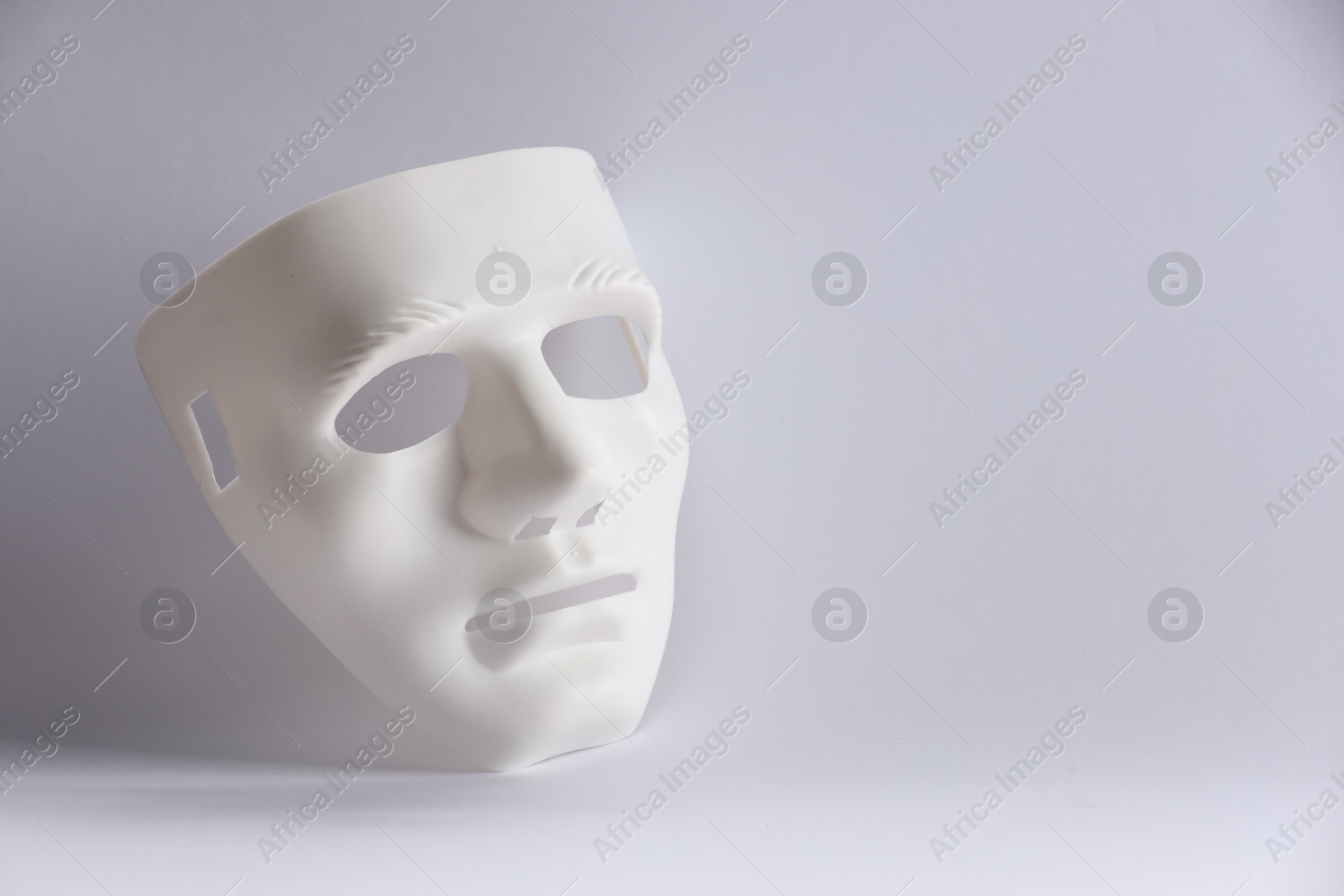 Photo of Plastic face mask on white background, space for text. Theatrical performance