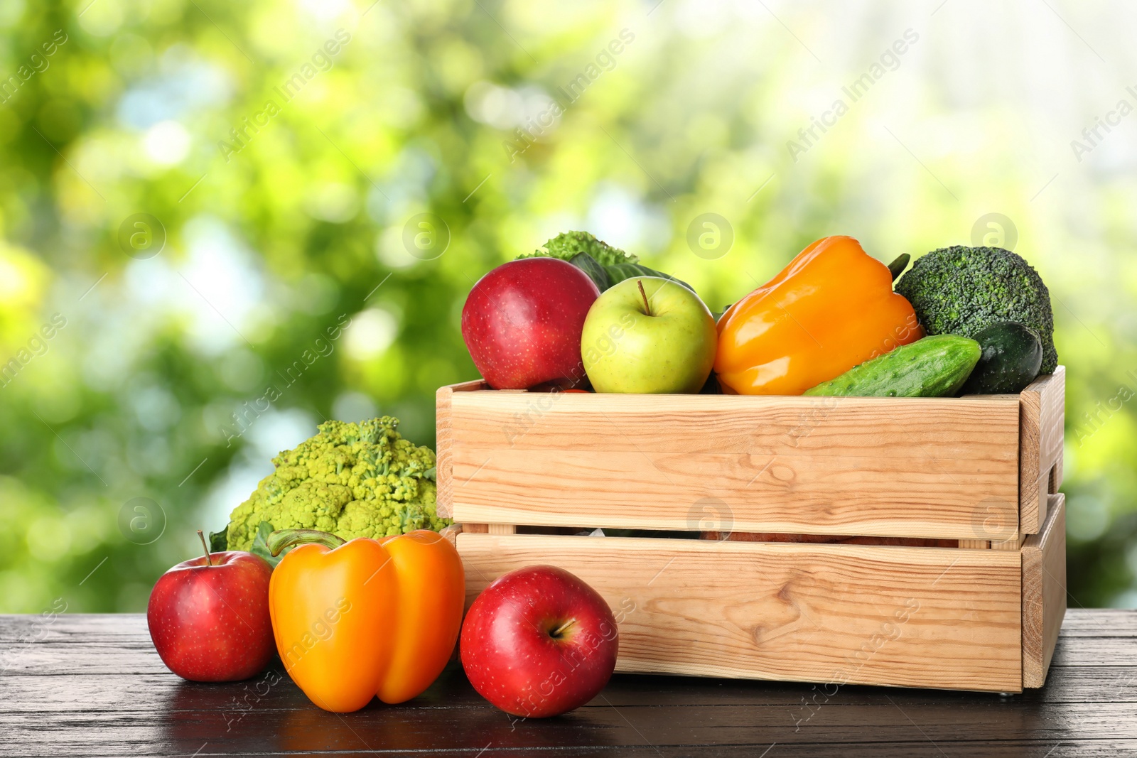 Image of Wooden crate with fresh vegetables and fruits on table against blurred background