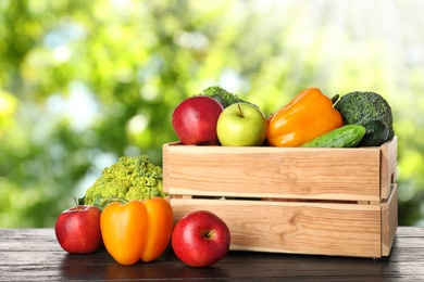 Image of Wooden crate with fresh vegetables and fruits on table against blurred background