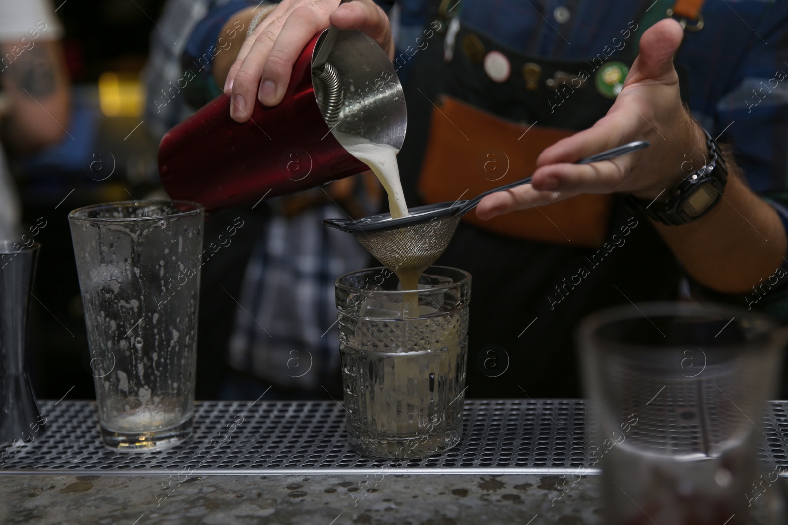 Photo of Bartender pouring tasty cocktail at counter in nightclub, closeup