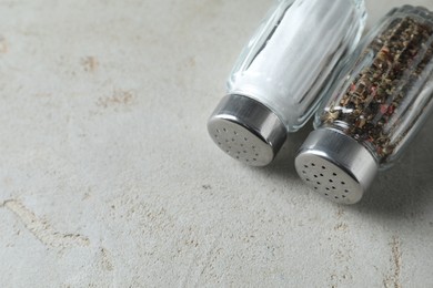 Photo of Salt and pepper shakers on light textured table. Space for text