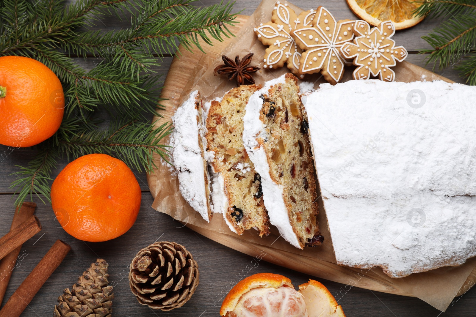 Photo of Traditional Christmas Stollen with icing sugar on wooden table, flat lay