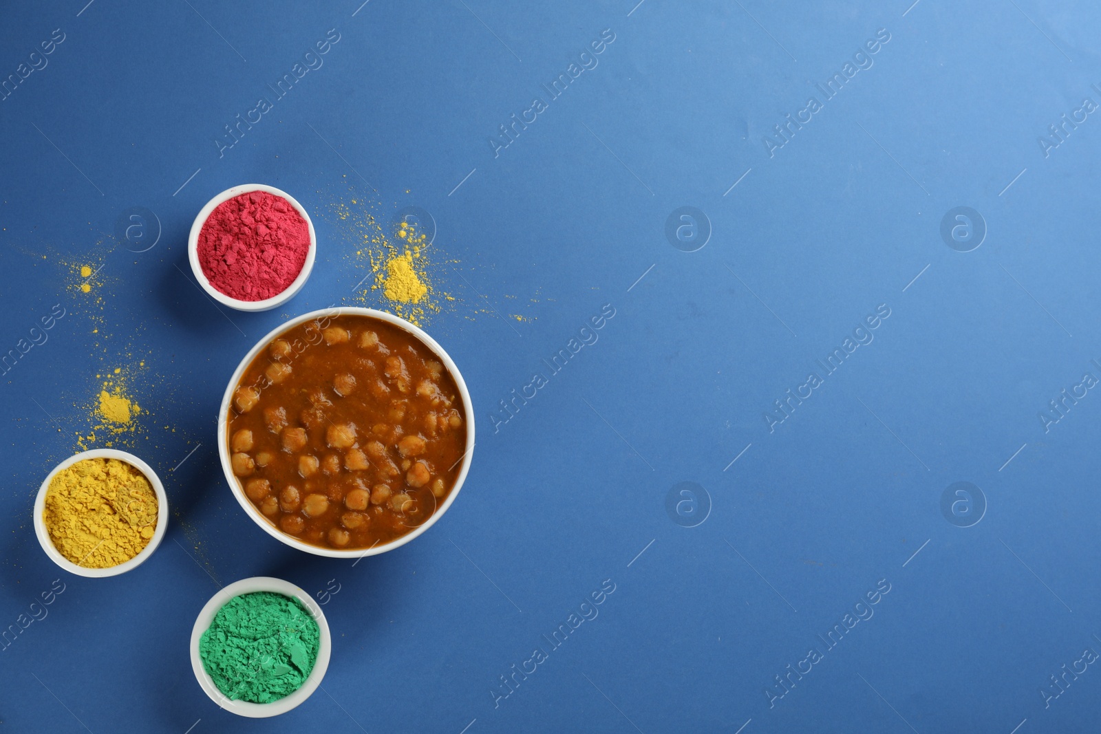 Photo of Flat lay of traditional Indian food and color powder dyes on blue background, space for text. Holi festival