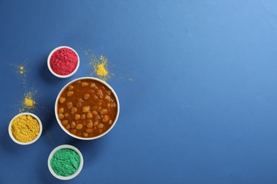 Photo of Flat lay of traditional Indian food and color powder dyes on blue background, space for text. Holi festival