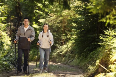 Photo of Couple with trekking poles hiking in forest