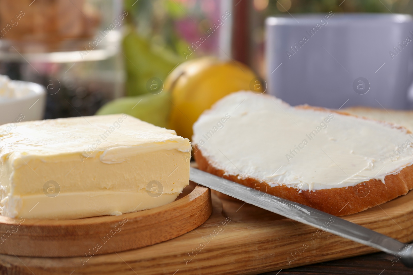 Photo of Tasty homemade butter, bread slices and tea on wooden table, closeup