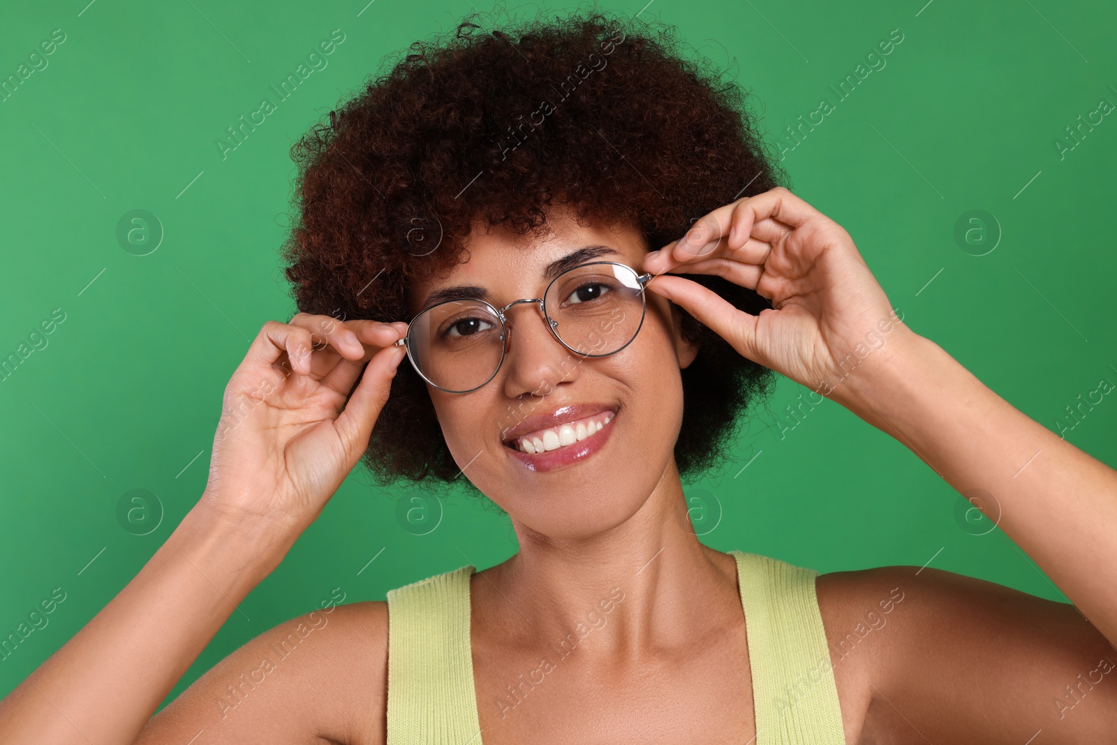 Photo of Portrait of happy young woman in eyeglasses on green background