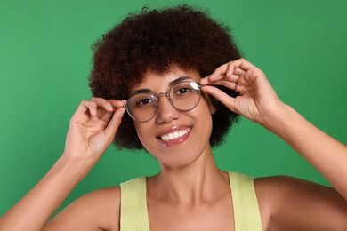 Portrait of happy young woman in eyeglasses on green background