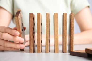 Photo of Woman with wooden dominoes at white table, closeup
