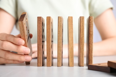 Woman with wooden dominoes at white table, closeup