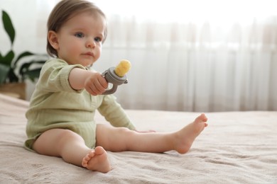 Cute baby girl with nibbler on bed at home. Space for text