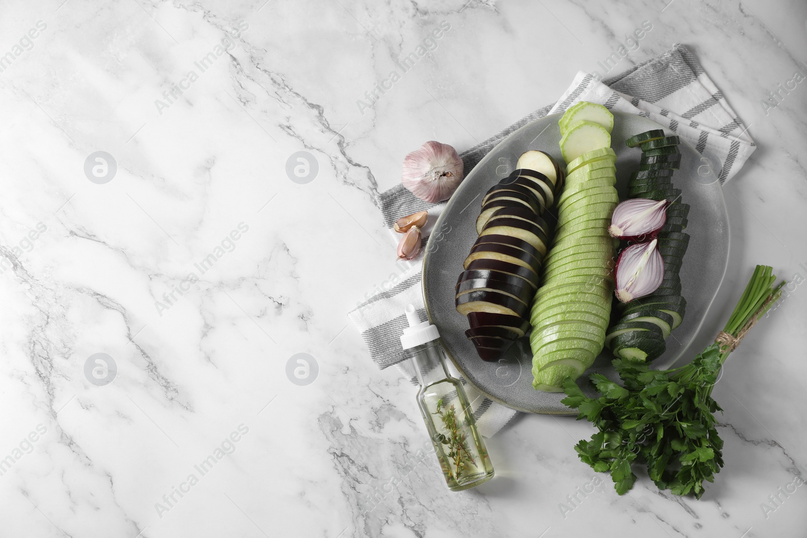 Photo of Cooking delicious ratatouille. Fresh ripe vegetables and plate on white marble table, flat lay. Space for text