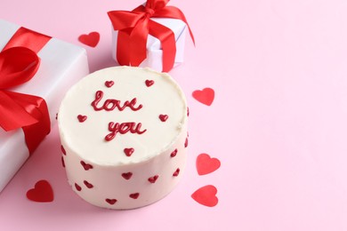 Photo of Bento cake with text Love You, gift boxes and paper hearts on pink table, space for text. St. Valentine's day surprise