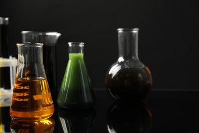 Photo of Laboratory glassware with different types of oil on black background