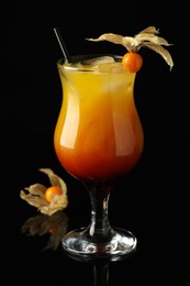 Tasty cocktail decorated with physalis fruit on black background