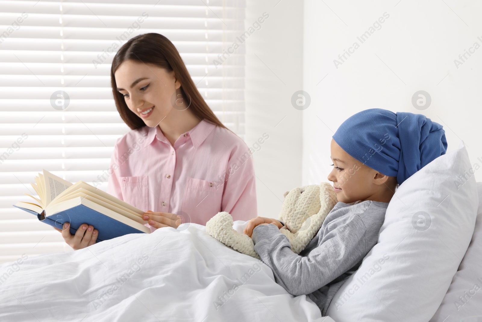 Photo of Childhood cancer. Mother reading book to daughter in hospital