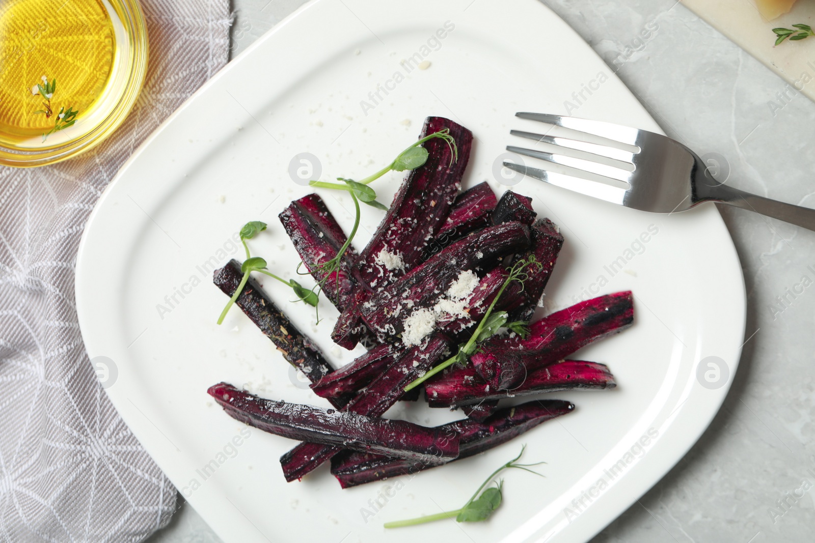 Photo of Tasty baked black carrot served on light grey marble table, flat lay