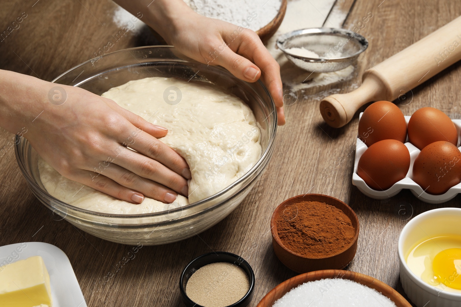 Photo of Woman kneading yeast dough for cake at wooden table, closeup