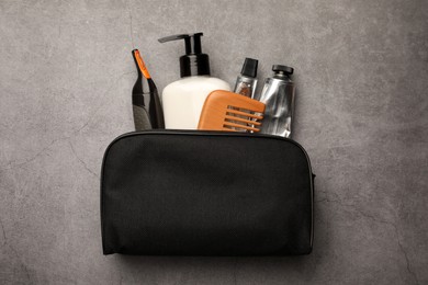 Preparation for spa. Compact toiletry bag with different cosmetic products on grey textured background, top view