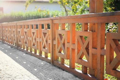 Photo of Beautiful wooden fence near green plants on sunny day outdoors