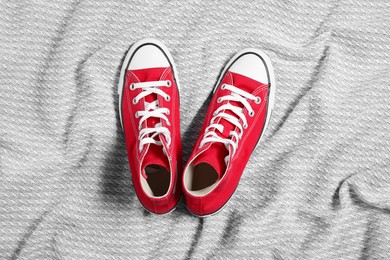 Pair of new stylish red sneakers on light grey fabric, flat lay