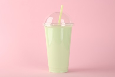 Plastic cup of tasty smoothie on pink background