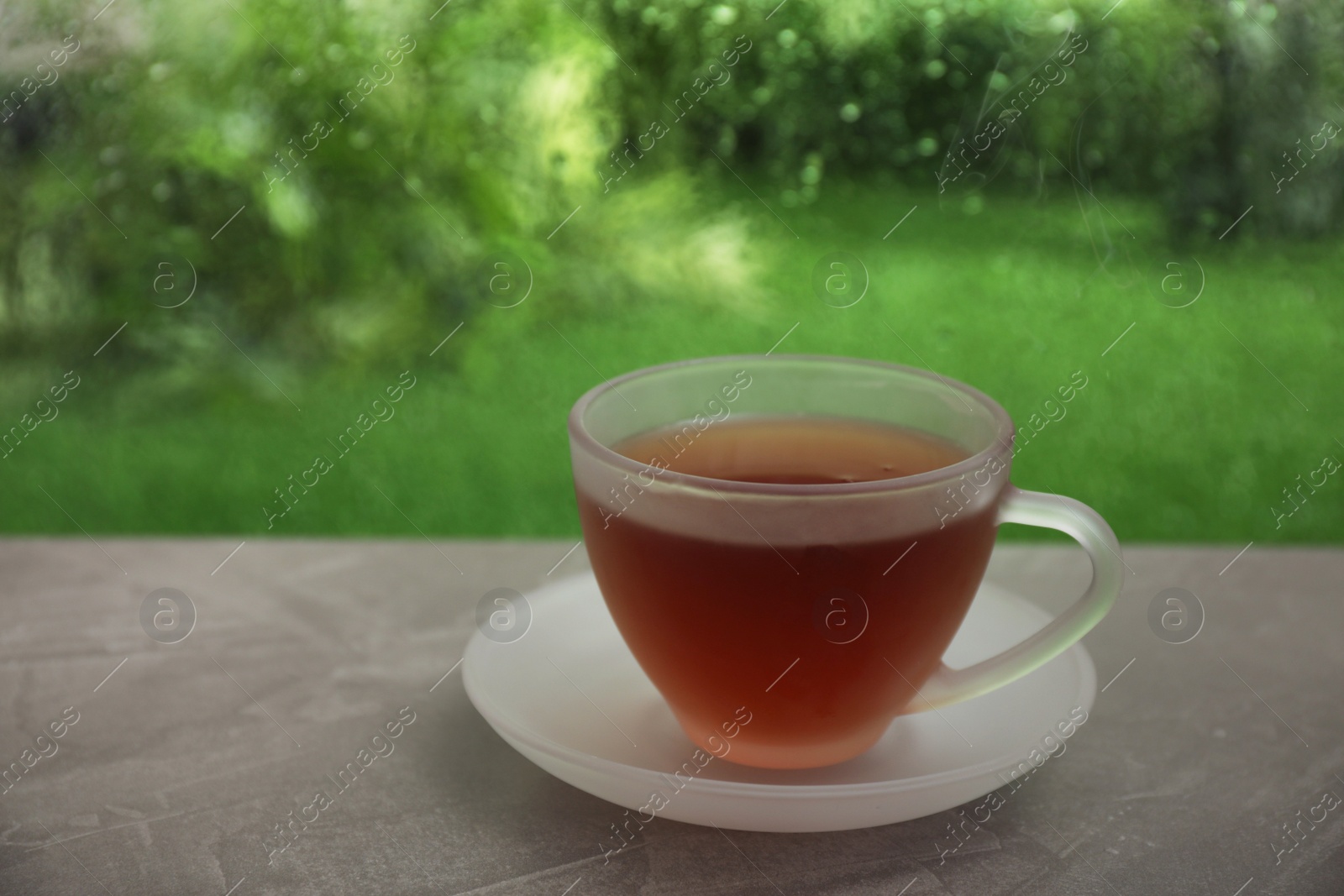 Photo of Cup of hot tea on brown windowsill, space for text. Rainy weather