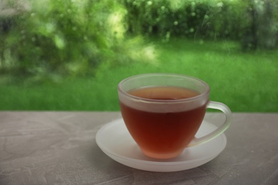 Photo of Cup of hot tea on brown windowsill, space for text. Rainy weather