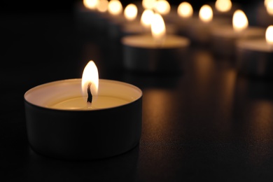 Photo of Burning candle on table in darkness, closeup with space for text. Funeral symbol