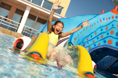 Photo of Happy girl on slide at water park. Summer vacation