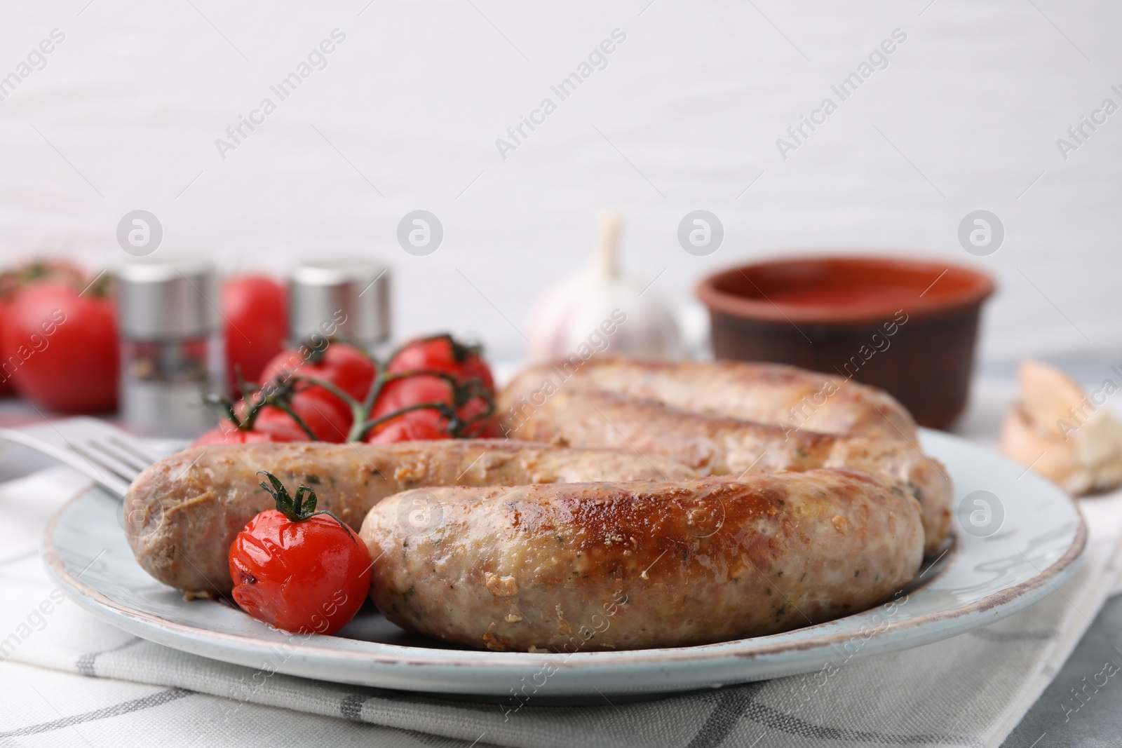 Photo of Plate with tasty homemade sausages and tomatoes on table, closeup