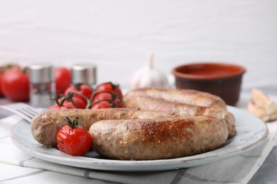 Photo of Plate with tasty homemade sausages and tomatoes on table, closeup