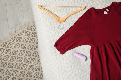 Photo of Female roll-on deodorant and clothes on bed, top view. Space for text