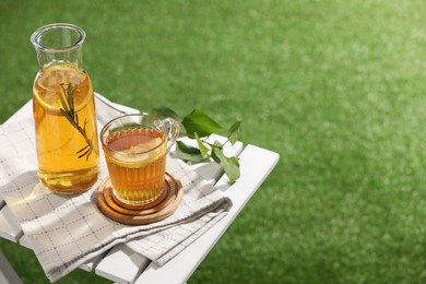 Glass bottle and cup of tasty iced tea on white wooden table outdoors, space for text