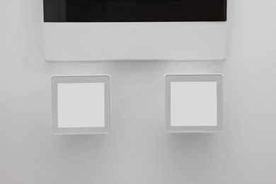 Photo of Modern thermostats on white wall. Smart home system