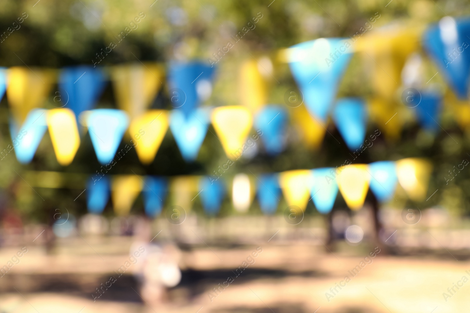 Photo of Blurred view of colorful bunting flags in park. Party decor