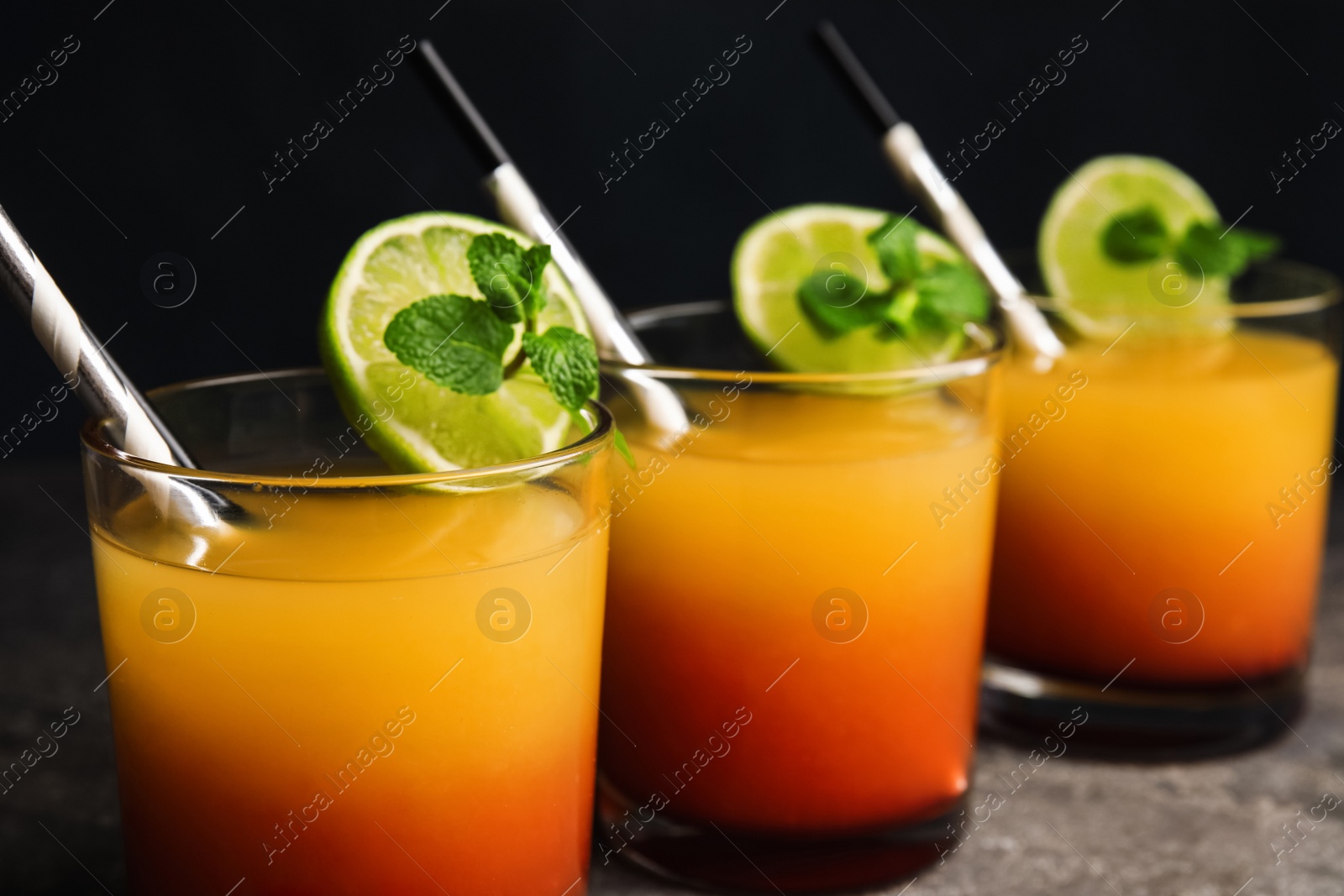 Photo of Fresh alcoholic Tequila Sunrise cocktails on grey table, closeup