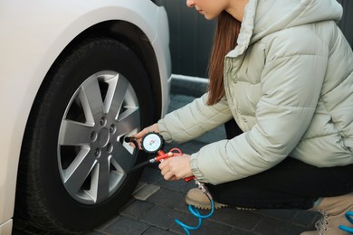 Young woman inflating tire at car service, closeup