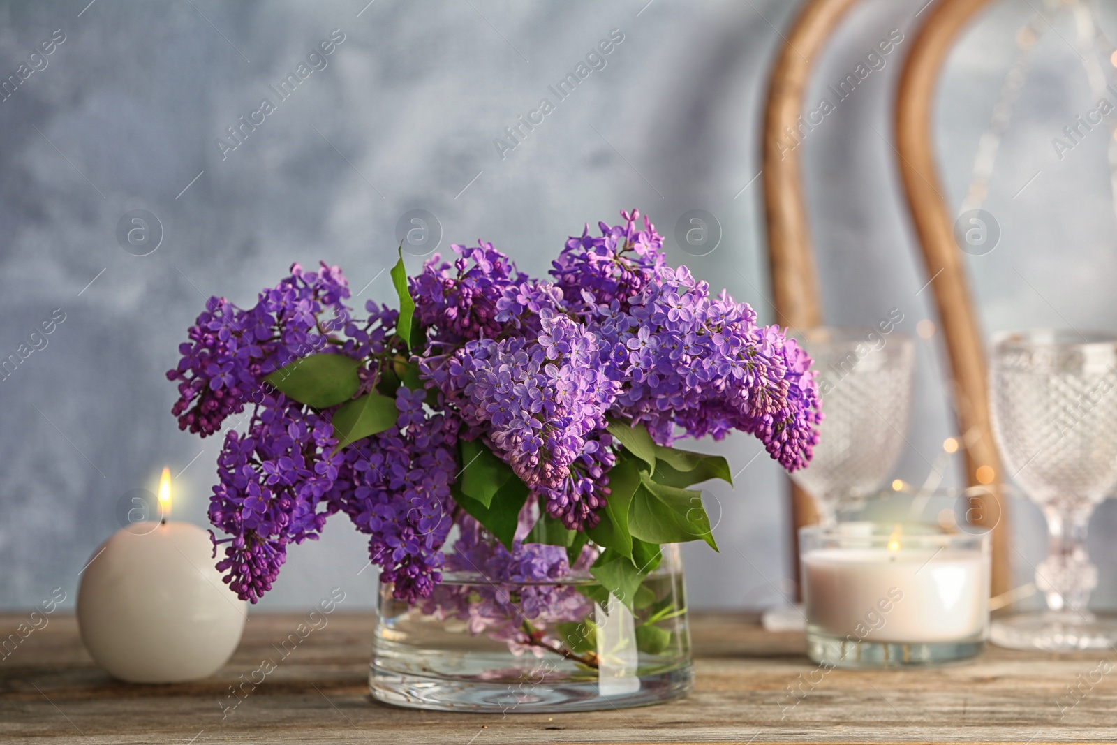 Photo of Vase with blossoming lilac on table indoors. Spring flowers