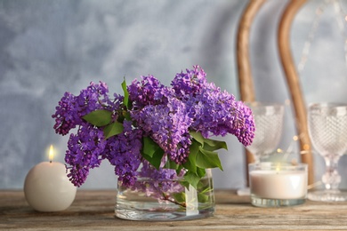 Photo of Vase with blossoming lilac on table indoors. Spring flowers