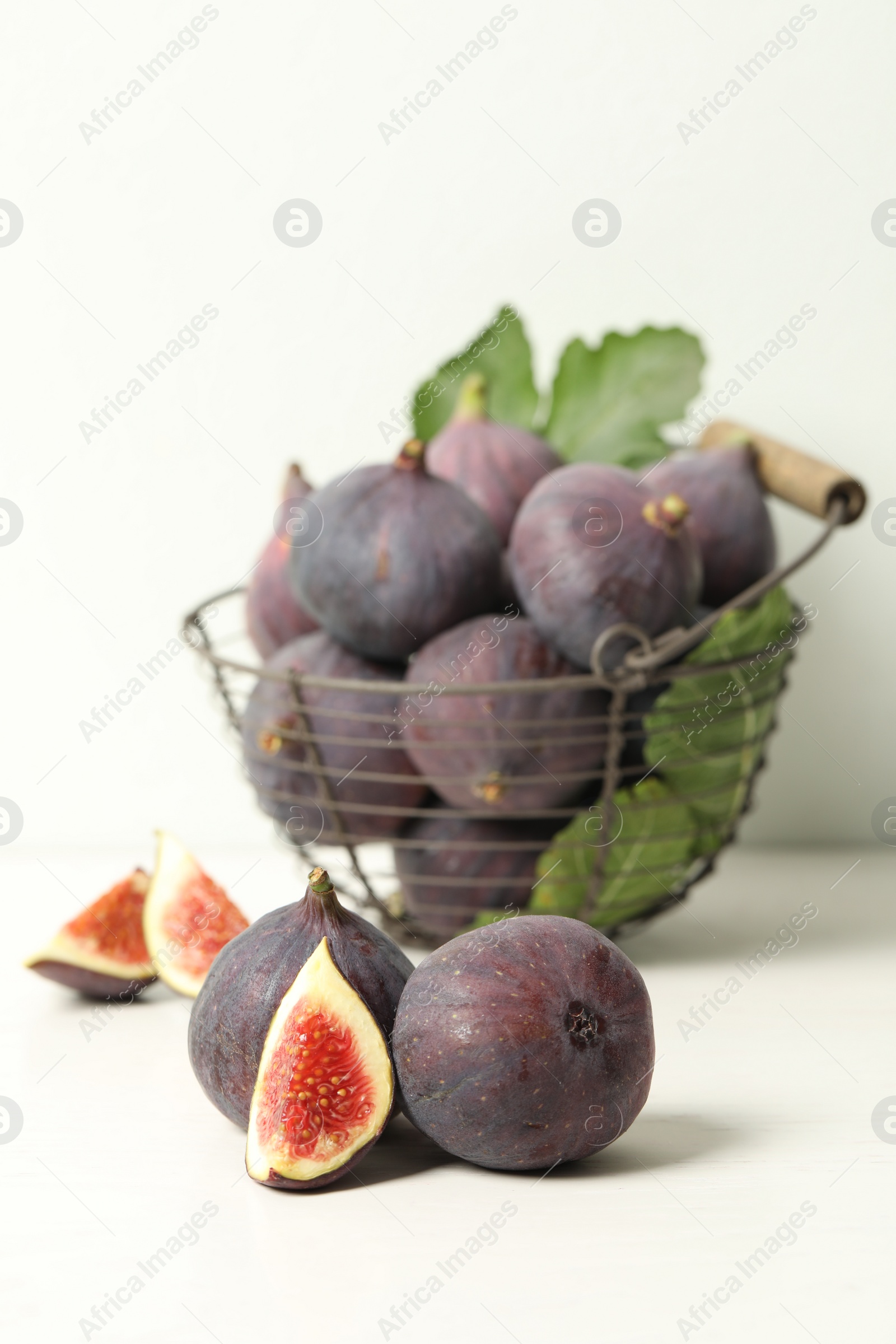 Photo of Whole and cut tasty fresh figs on white table