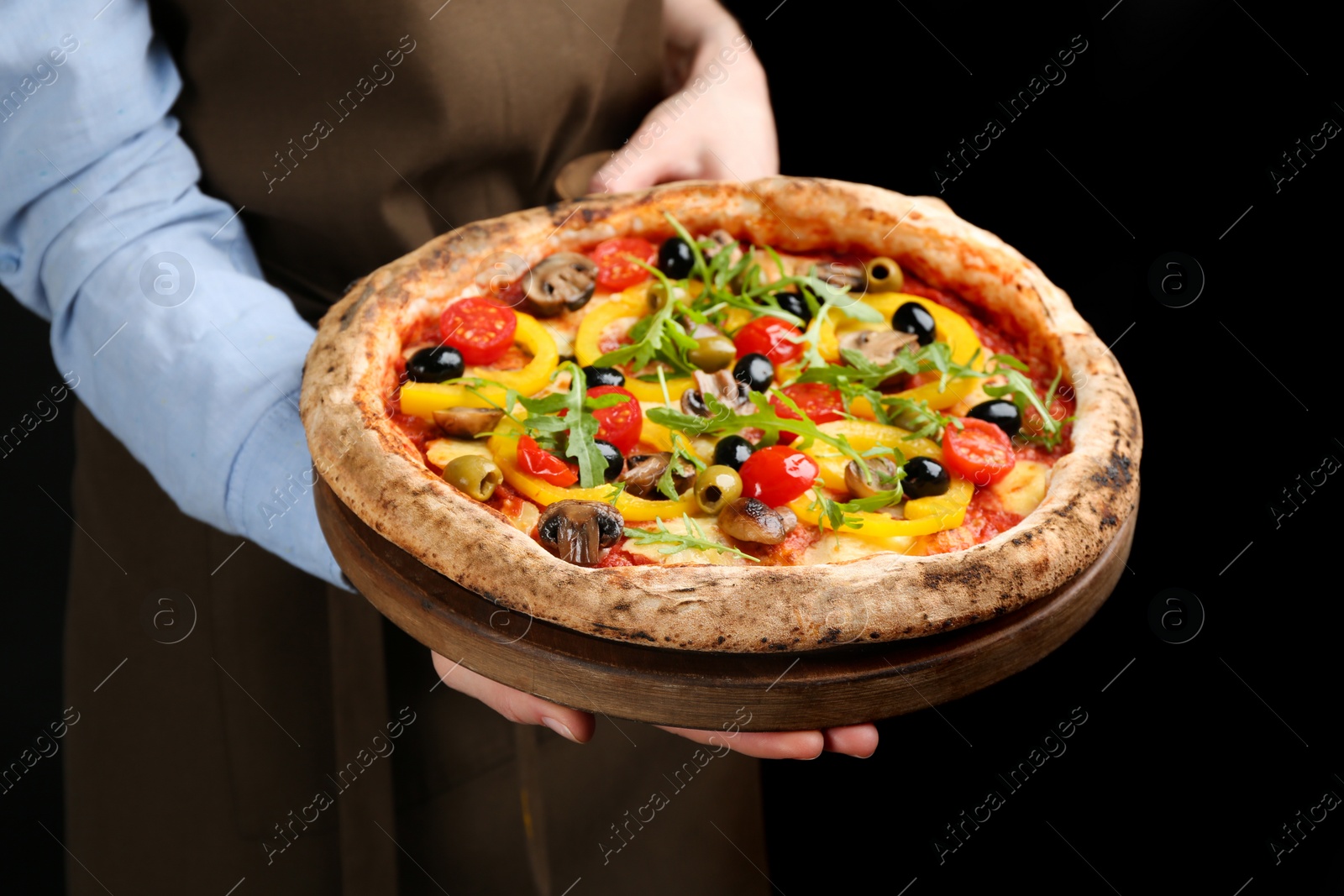 Photo of Woman holding tasty vegetable pizza on black background, closeup