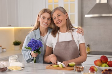 Photo of Daughter with beautiful cornflowers visiting her mature mother at home