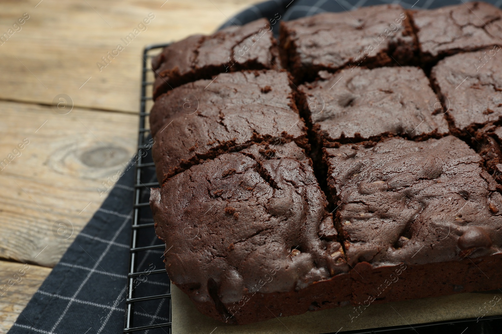 Photo of Cooling rack with delicious freshly baked brownies on wooden table, closeup