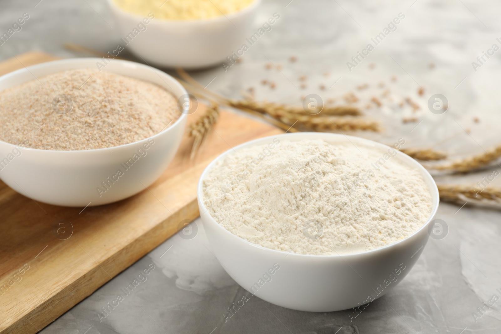 Photo of Bowls with different flours on light grey table