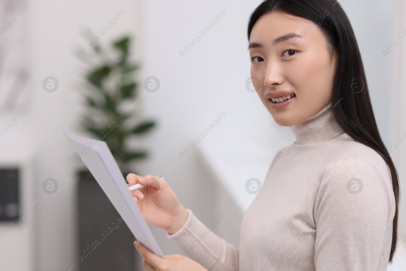 Photo of Portrait of smiling businesswoman with documents in office