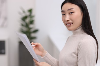 Photo of Portrait of smiling businesswoman with documents in office